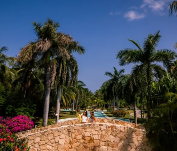 Guests walking across a stone bridge
surrounded by lush tropical landscaping at El Dorado Royale Riviera Maya in
Mexico.